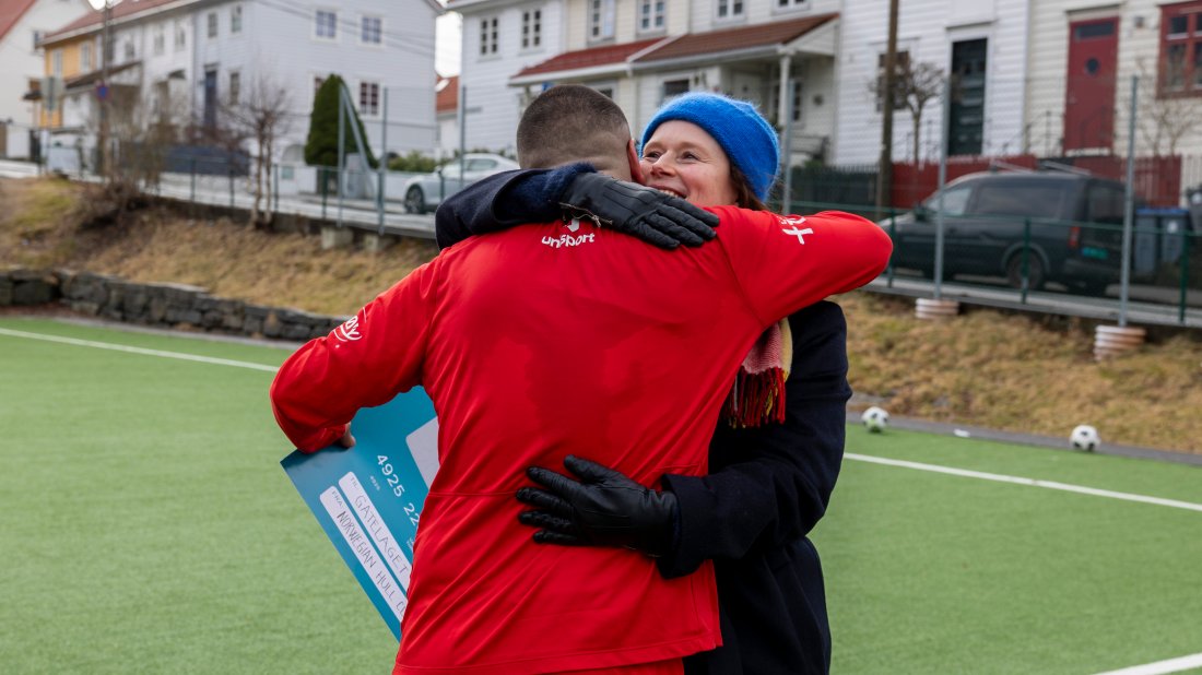 Hildegunn Nilssen fikk en god klem av kapteinen på Gatelaget etter overrekkelsen av sjekken. Foto: Brann.no.
